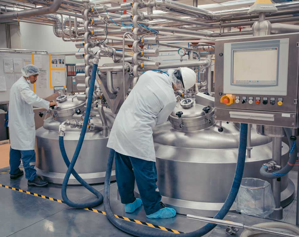 Two workers wearing PPEs, inspecting food and beverage equipment in lab